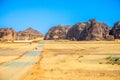 Desert sand landscape with mountains in the background and road with cars, near Al Ula, Saudi Arabia