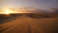 Desert at sunset hour with dune buggy tires tracks in the sand in the foreground. Royalty Free Stock Photo