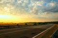 A deserted asphalt road going around the bend, at dawn among the fields. soft sunlight Royalty Free Stock Photo
