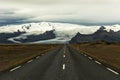 Deserted asphalt straight road on the background of glacial mountains. Landscapes of Iceland. The spirit of adventure and travel. Royalty Free Stock Photo