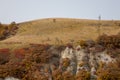 Deserted autumn plain in mountains with yellowed grass. Rocks on a slope in mountains. Mountainous area against blue sky