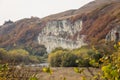 Deserted autumn plain in mountains with yellowed grass. Rocks on a slope in mountains. Mountainous area against blue sky