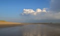 Deserted beach at low tide, with a jetty and dramatic sky in the