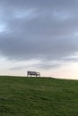 Deserted bench in front of a dark sky on a dam at the North Sea Royalty Free Stock Photo