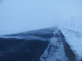Deserted paved winter road with snow and electric poles