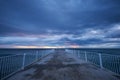 deserted pier with dramatic sky over stormy dark sea at sunrise Royalty Free Stock Photo