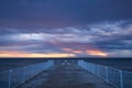 deserted pier with dramatic sky over stormy dark sea at sunrise Royalty Free Stock Photo