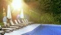 Deserted pool and sun loungers by the pool in the gentle rays of the morning sun. Place of rest and relaxation, summer mood. Royalty Free Stock Photo