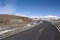 Deserted road and snowy mountains Royalty Free Stock Photo