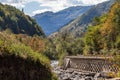 A deserted road with a supporting wall runs next to a small mountain river. Royalty Free Stock Photo