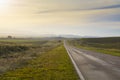 deserted route sunset road to the mountains covered by a blanket of mist