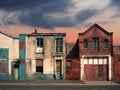 a deserted street of old abandoned ruined houses with bright peeling paint and crumbling brickwork in evening sunlight against a Royalty Free Stock Photo