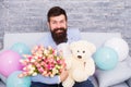 She deserve all best. Romantic man with flowers and teddy bear sit on couch with air balloons waiting girlfriend