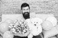 She deserve all best. Romantic man with flowers and teddy bear sit on couch with air balloons waiting girlfriend