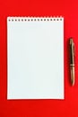 Top view of a spiral school notebook and pen collection on a red background for layout