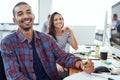 Design is in our blood. Portrait of two smiling designers sitting at their workstations in an office.