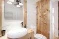 Design toilet with oblong porcelain sink on pine wood furniture and marble tiles