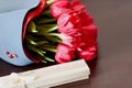 Designed bouquet of fresh red tulips with a gift box on light green background