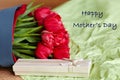 Designed bouquet of fresh red tulips with a gift box on light green background with text Happy Mother`s Day.