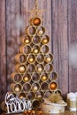 Designer Christmas tree with toys and gifts on a wooden background with candles