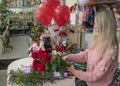 Designer florist makes a bouquet of red roses for Valentine`s day on the background of the interior of a flower shop