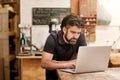 Designer in his workshop typing on a laptop