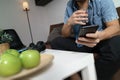 designer man hand using mobile payments online shopping,omni channel,drinking water,sitting on sofa in living room,green apples i Royalty Free Stock Photo