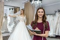 Designer with notepad and bride in wedding dress behind Royalty Free Stock Photo