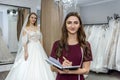 Designer with notepad and bride in wedding dress behind Royalty Free Stock Photo