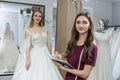 Designer with notepad and bride in wedding dress behind Royalty Free Stock Photo