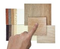 designer's hand chooses interior material samples contains oak wooden ceramic flooring tiles and drapery fabric catalog. Royalty Free Stock Photo