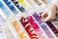 Designer selecting fabric color samples from palette book on table. Creativity, craftsmanship, and fashion design process in Royalty Free Stock Photo