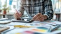 A designer sketching ideas on a tablet while seated at a workspace cluttered with creative materials during the afternoon Royalty Free Stock Photo