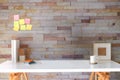 Designer workplace, pencil holder, books, picture frame and coffee cup on white table with brick wall Royalty Free Stock Photo