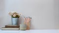 Designer workspace with pencils notebook, coffee cup,vase and copy space on white table. Royalty Free Stock Photo