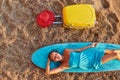 Desire of adventure, summer time, surf and holiday trip idea. Cute woman lay on surfboard, suitcase and hat on sand Royalty Free Stock Photo