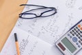 Desk with calculator glasses pens maths homework exercise book