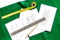 Desk of clothing designer. Green textile and pattern of clothing on white background top view