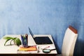 Desk with colored pencils, laptop, books, a magnifying glass and a plant at home or office Royalty Free Stock Photo