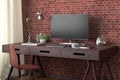 Desk with computer monitor. Workplace in the studio or at home with red brick wall. Royalty Free Stock Photo