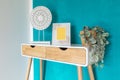 Desk detail with two drawers, yellow frame, plant and turquoise wall. Front view Royalty Free Stock Photo