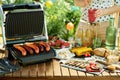 Desk with electric grill and grilled sausages Royalty Free Stock Photo