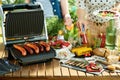 Desk with electric grill and grilled sausages Royalty Free Stock Photo