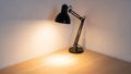Desk lamp on a light wooden surface illuminating a corner of the Royalty Free Stock Photo