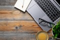 Desk with laptop, eyeglasses, notepad, pen and a cup of coffee on a old wooden table. Top view with copy space. Flat lay. Dark woo Royalty Free Stock Photo