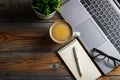 Desk with laptop, eyeglasses, notepad, pen and a cup of coffee on a old wooden table. Top view with copy space. Flat lay. Dark woo