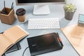 The gray desk with laptop, notepad with blank sheet, pot of flower, stylus and tablet for retouching Royalty Free Stock Photo