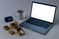 A desk with a laptop, small boxes, tea and an electronic clock. Space for text. Royalty Free Stock Photo