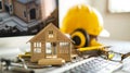 Desk with miniature house model, hard hat, blueprints, and tools