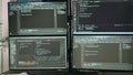 Desk with multiple monitors displaying terminal window and artificial intelligence